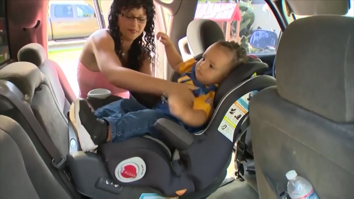 A woman buckles her child into his seat
