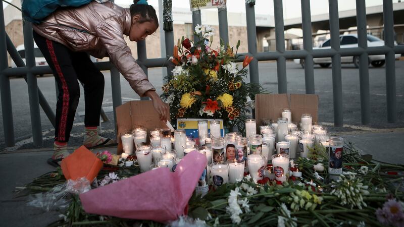 A girl lights candle during a vigil for the victims of a fire at an immigration detention...